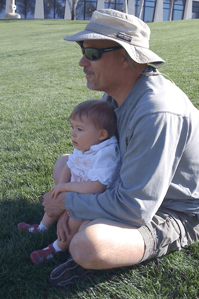 A man sitting on the grass with his baby.